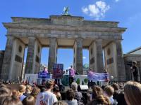 Menschen von Germanwatch bei einer Klimademo vor dem Brandenburger Tor mit Bannern und einem großen Foto von Saúl Luciano Lliuya