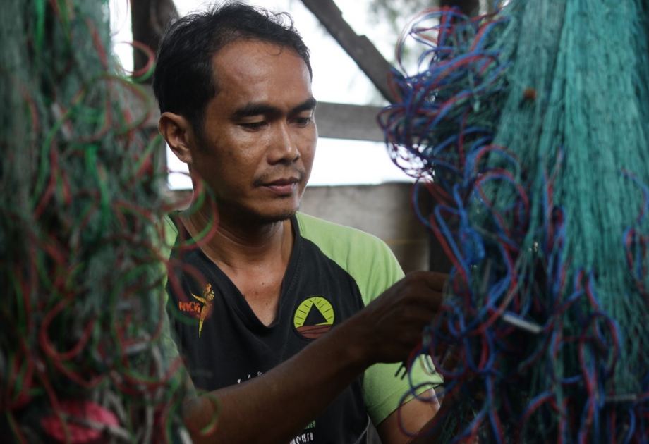 Climate plaintiff Edi Pari Island Holcim Climate plaintiff Edi from Indonesia mends his fishing net
