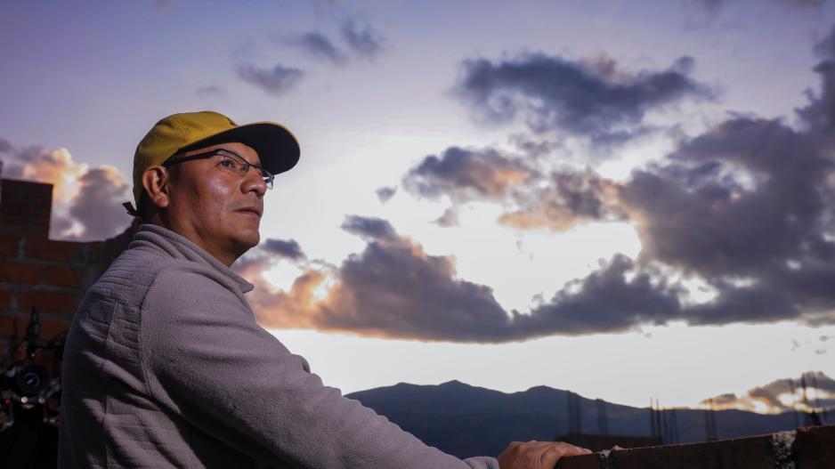 Saúl Luciano Lliuya stands on the roof of his house and looks into the Cordillera Blanca