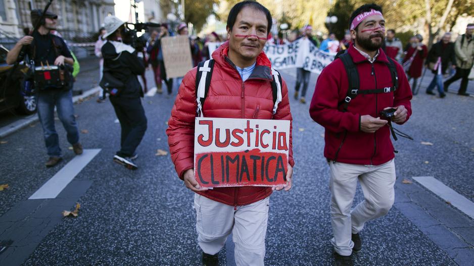 Saúl Luciano Lliuya auf einer Demonstration mit einem Schild "Justicia Climatica" (auf Deutsch: Klimagerechtigkeit)